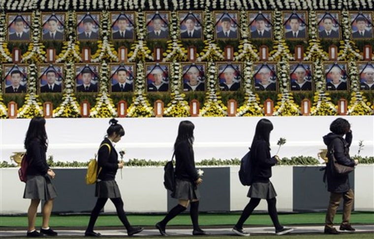 South Korean mourners arrive to pay a tribute in front of portraits of the deceased sailors from the sunken South Korean naval ship Cheonan during a memorial service held at Seoul City Hall Plaza in Seoul, South Korea on Thursday.